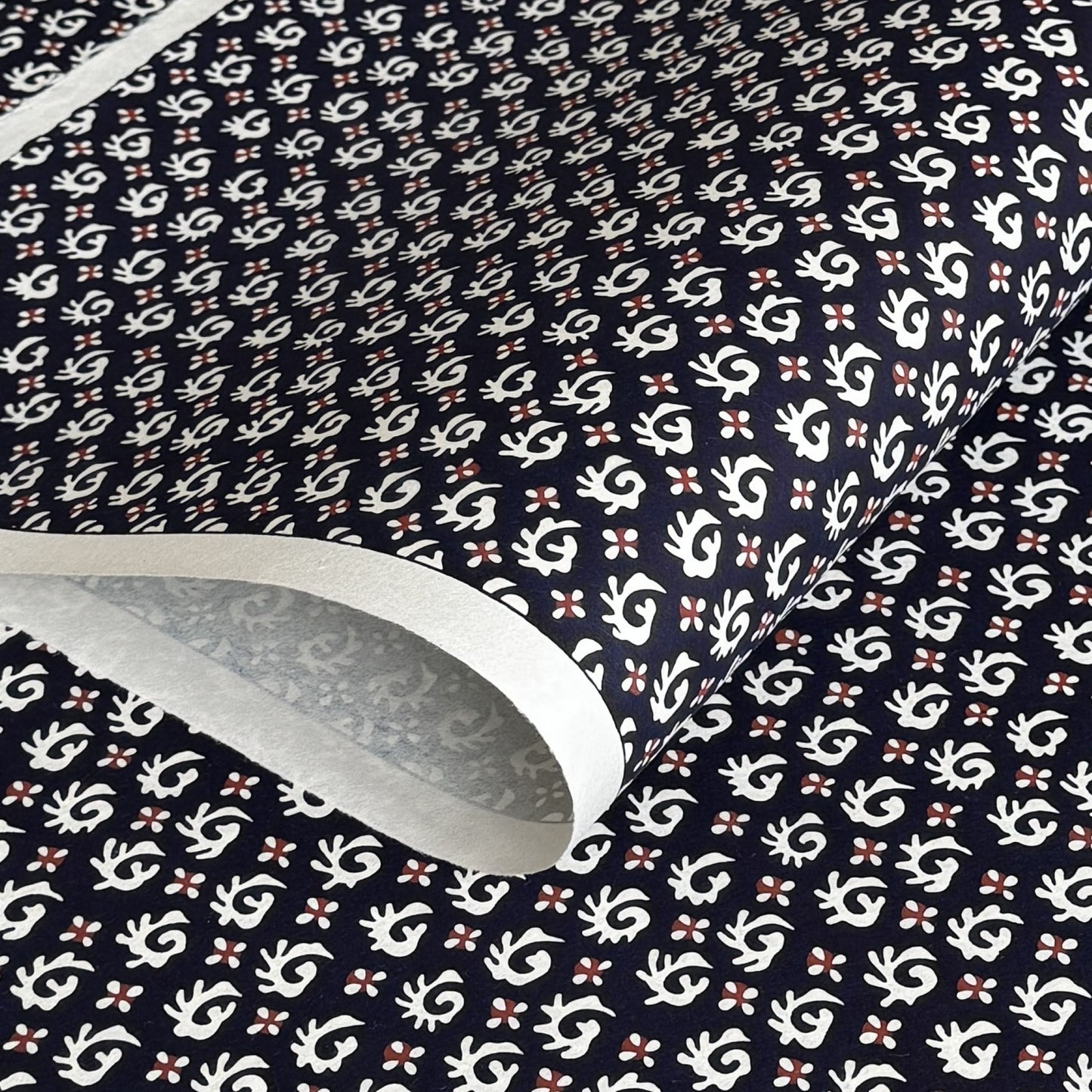 japanese stencil-dyed paper with a white swirl geometric repeat pattern on a dark inky blue background