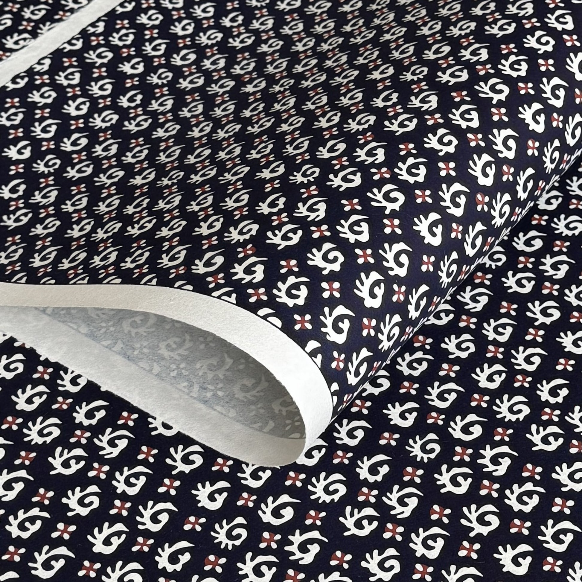 japanese stencil-dyed paper with a white swirl geometric repeat pattern on a dark inky blue background