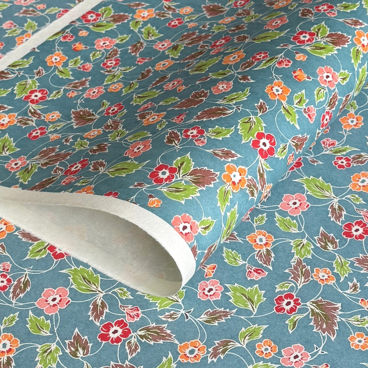 japanese stencil-dyed handmade paper with delicate repeat multi colour floral pattern on blue backdrop