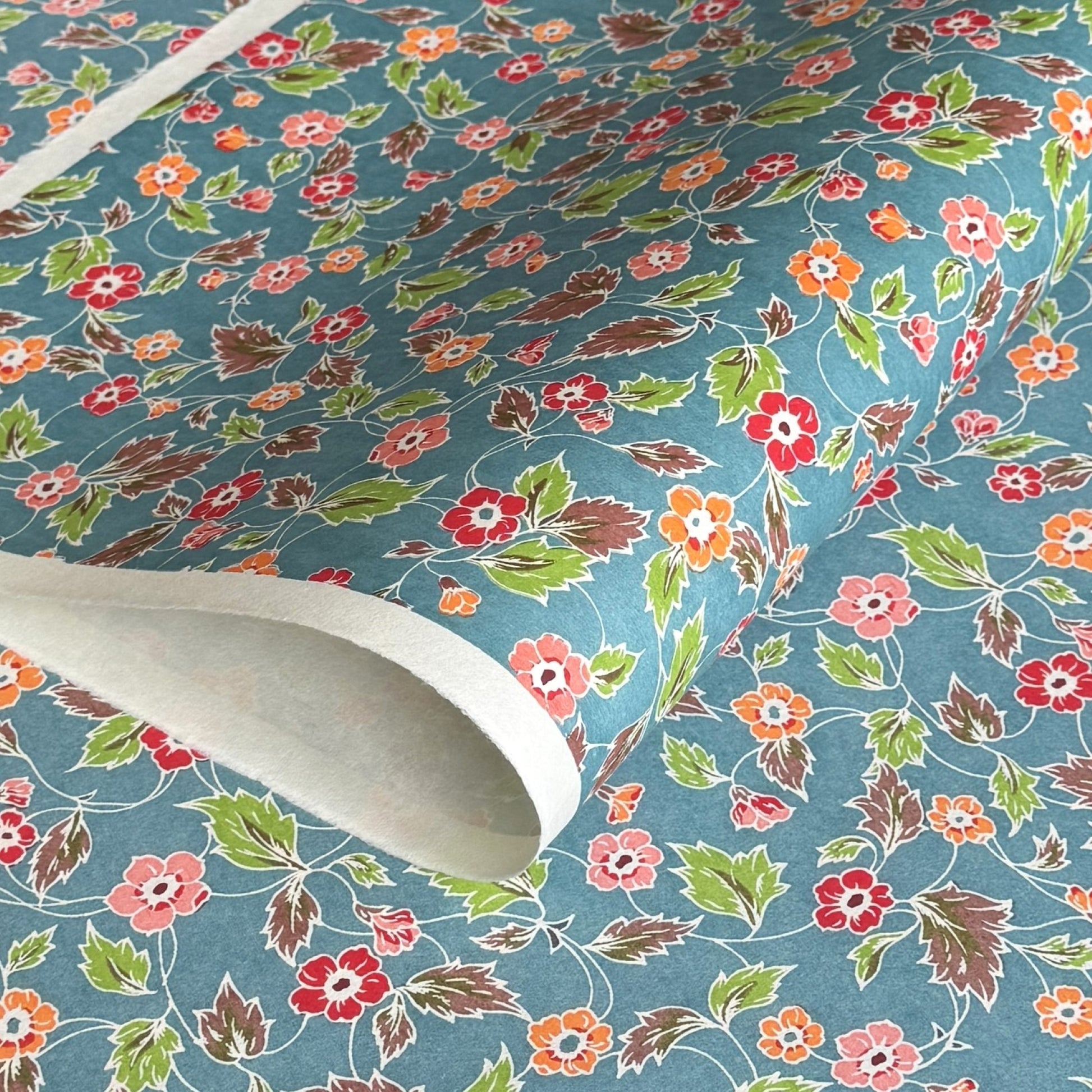 japanese stencil-dyed handmade paper with delicate repeat multi colour floral pattern on blue backdrop