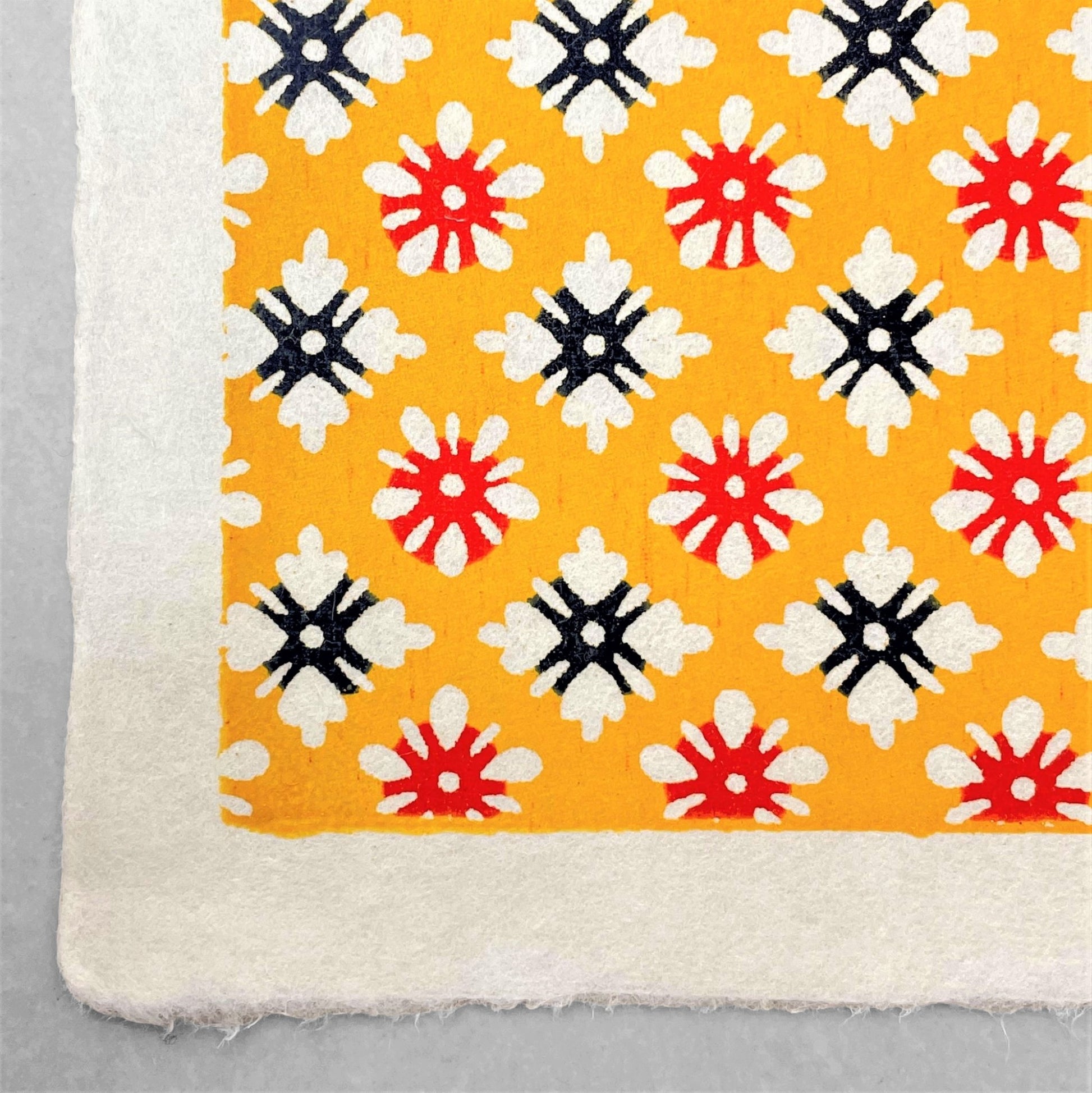 japanese stencil-dyed handmade paper with small scale floral repeat pattern on yellow backdrop
