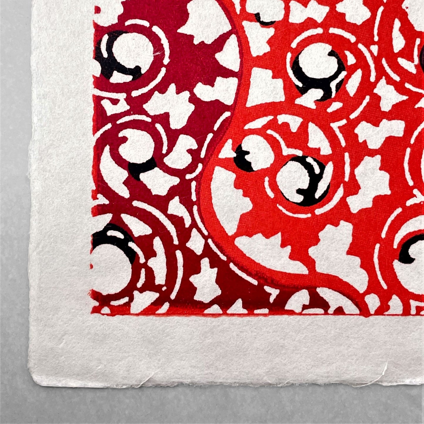 japanese stencil-dyed handmade paper with traditional arabesque vine pattern in red and maroon