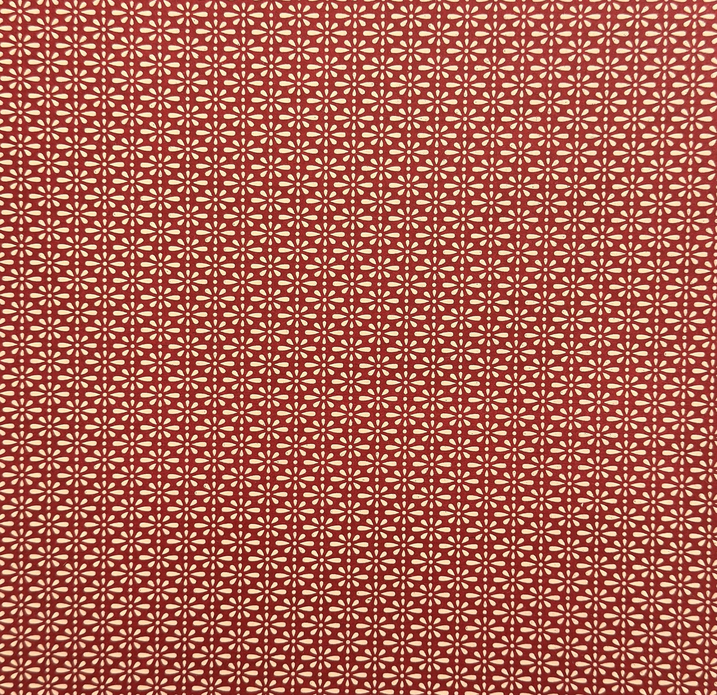 A sheet of Japanese lacquered yuzen paper in red with a repeat geometric flower pattern in cream