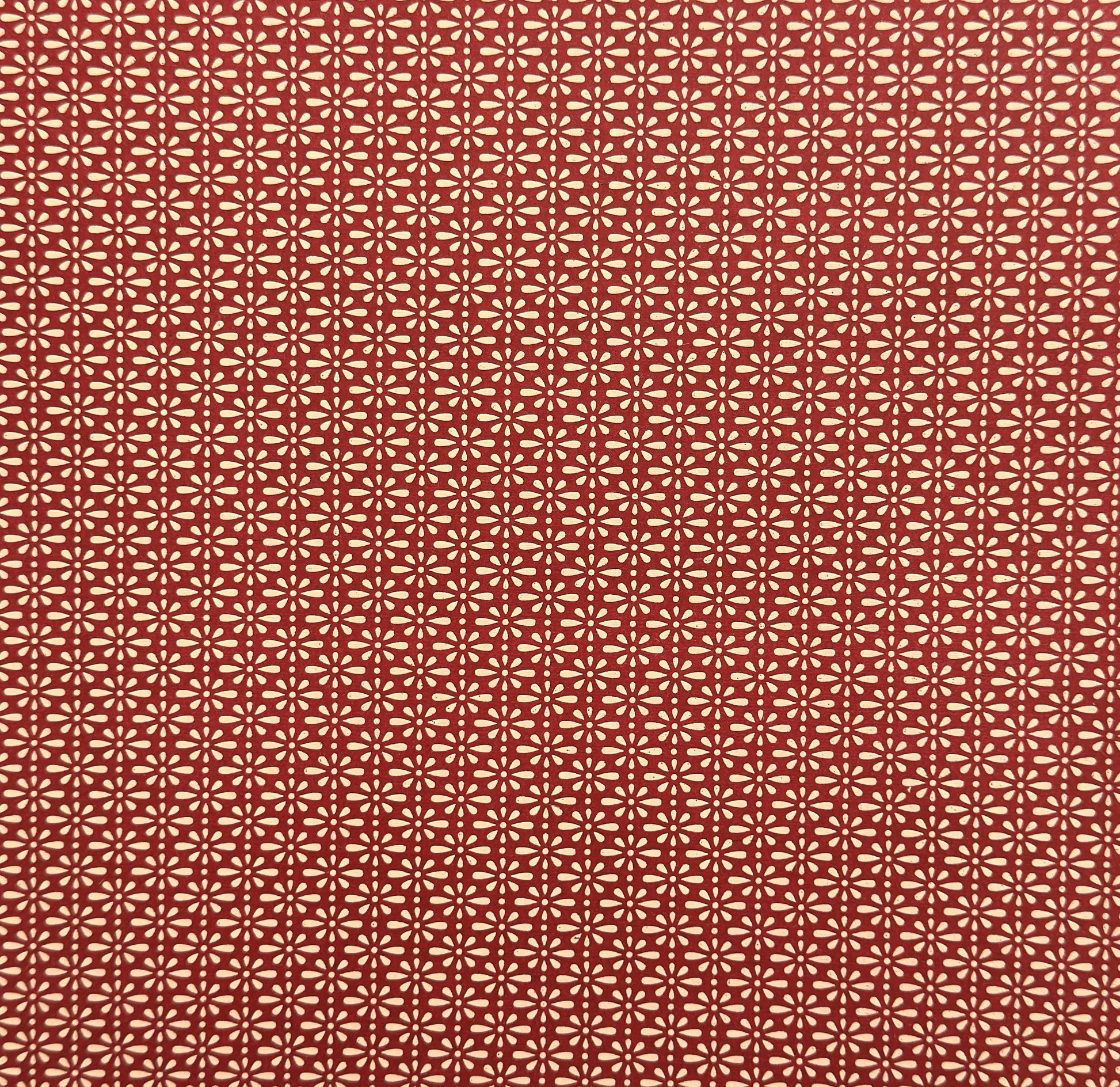 A sheet of Japanese lacquered yuzen paper in red with a repeat geometric flower pattern in cream