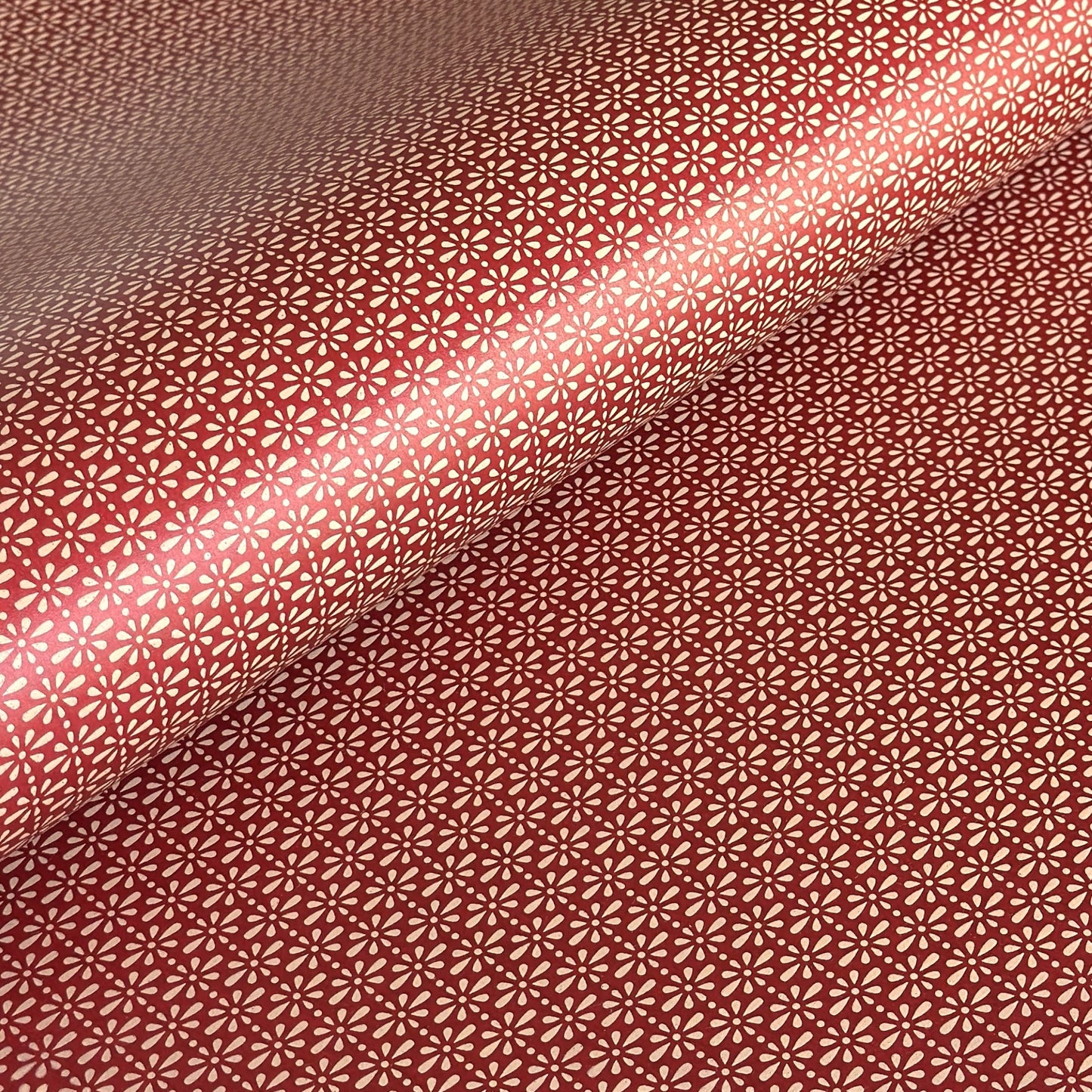 A sheet of Japanese lacquered yuzen paper in red with a repeat geometric flower pattern in cream