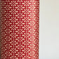 A sheet of Japanese lacquered yuzen paper in red with a repeat geometric flower pattern in cream