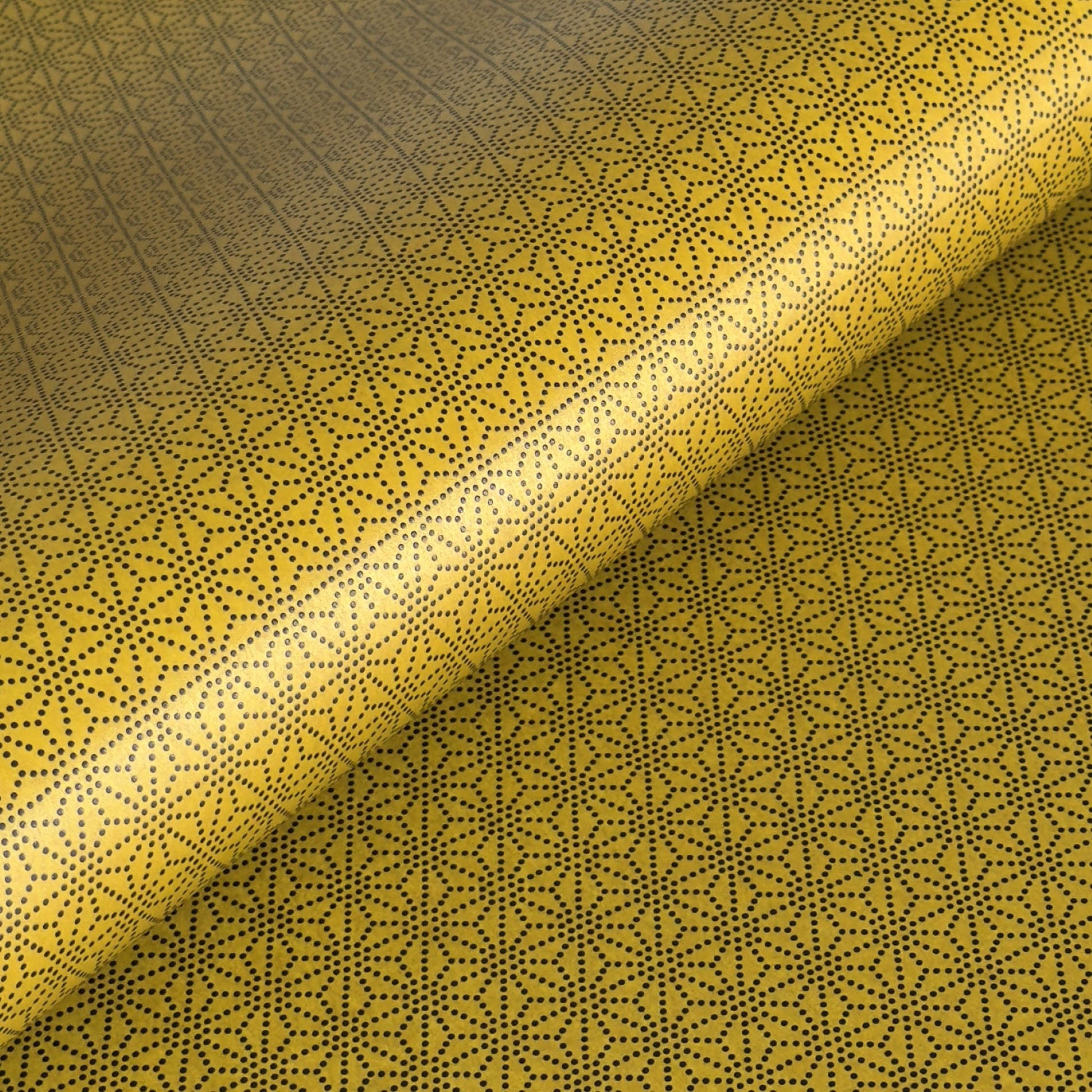 a sheet of Japanese lacquered yuzen paper with a mustard yellow background and a geometric dotted star pattern in black