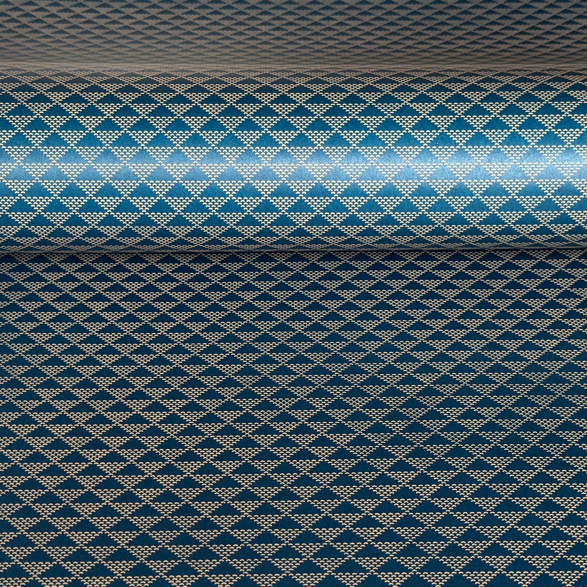 A sheet of Japanese lacquered yuzen paper in deep teal with a repeat small triangle geometric pattern in cream