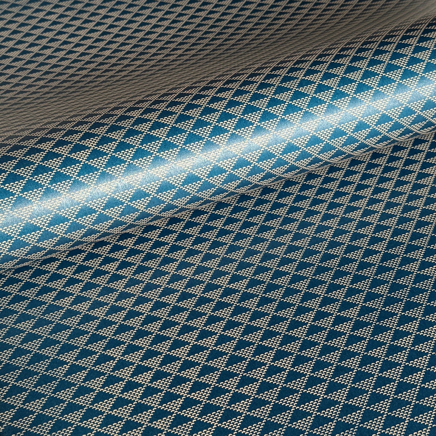 A sheet of Japanese lacquered yuzen paper in deep teal with a repeat small triangle geometric pattern in cream