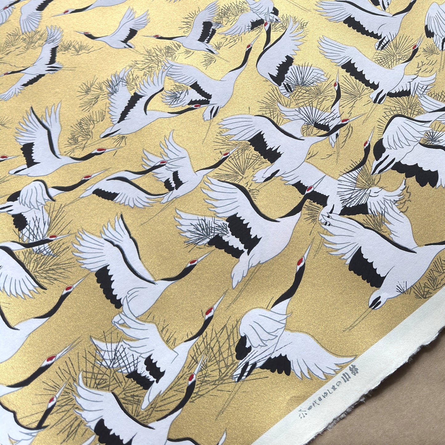 a sheet of Japanese Sogara yuzen paper with an image of white and black flying cranes on a gold background.