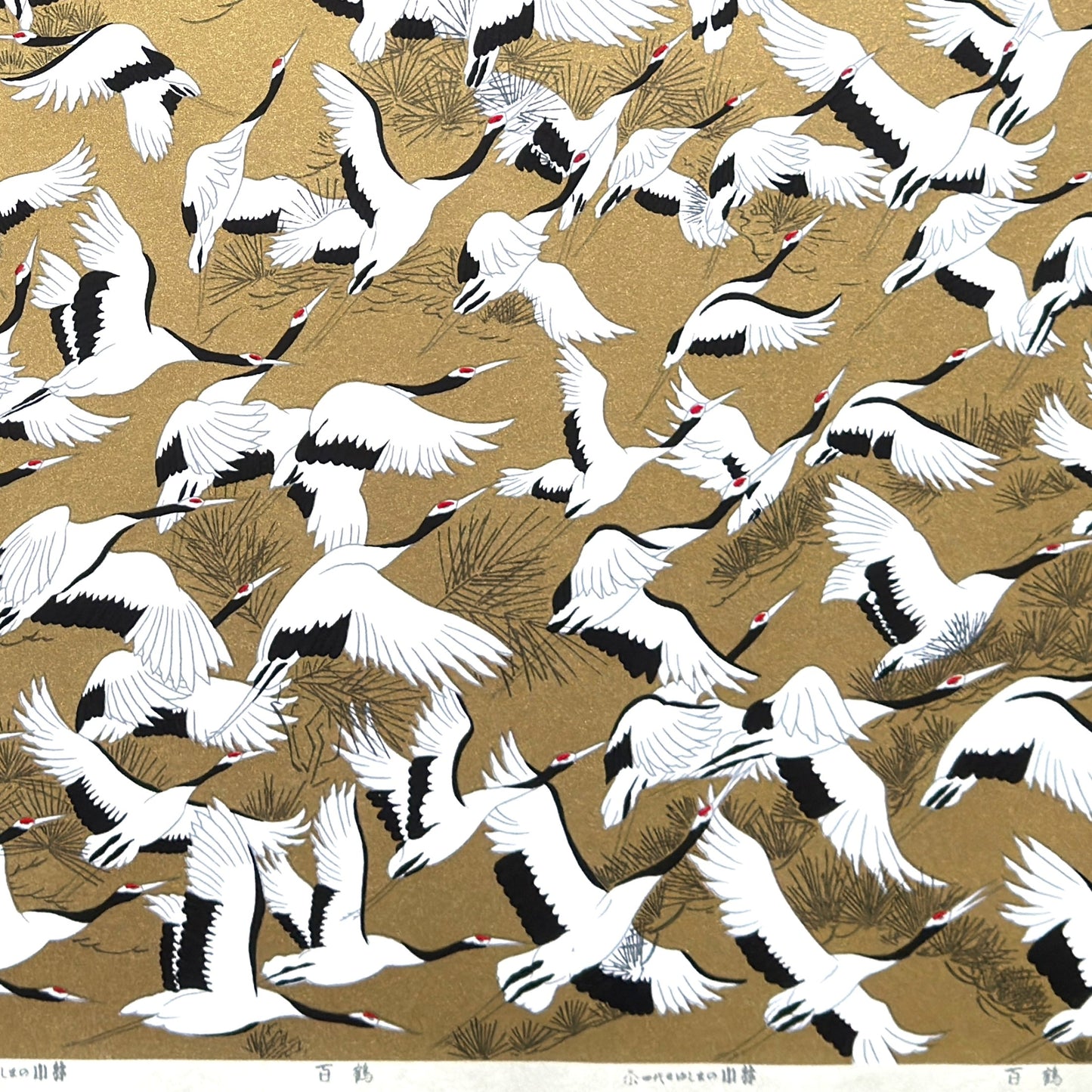 a sheet of Japanese Sogara yuzen paper with an image of white and black flying cranes on a gold background.