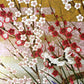 A sheet of Japanese silkscreen printed paper called Sogara which depicts white cranes flying in a pink and gold sky, surrounded by blossom and flowers. close up of plum blossom