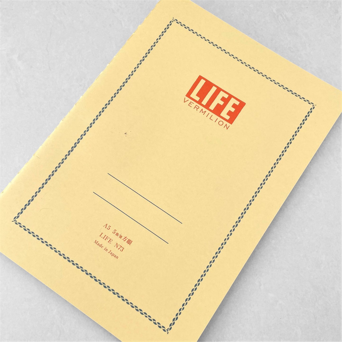 A5 softcover notebook with a soft yellow cover with blue border and branding by Japanese brand Life Japan