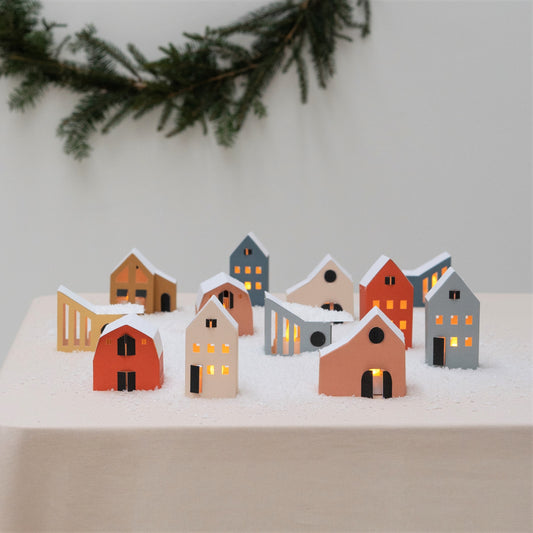 set of 12 colourful paper houses by Jurianne Matter, pictured on a table with snow