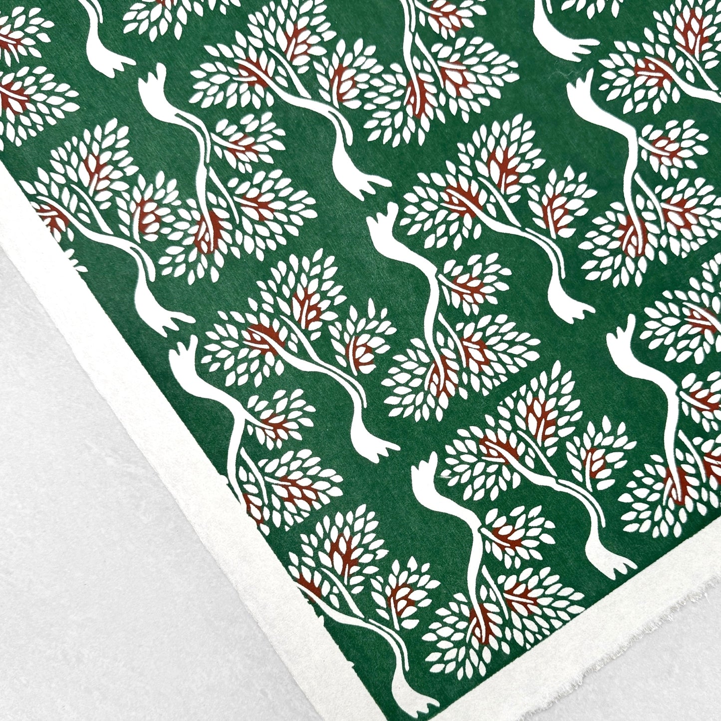 A Japanese stencil-dyed patterned paper in dark green with a repeat pattern of white bonsai trees. Flat shot