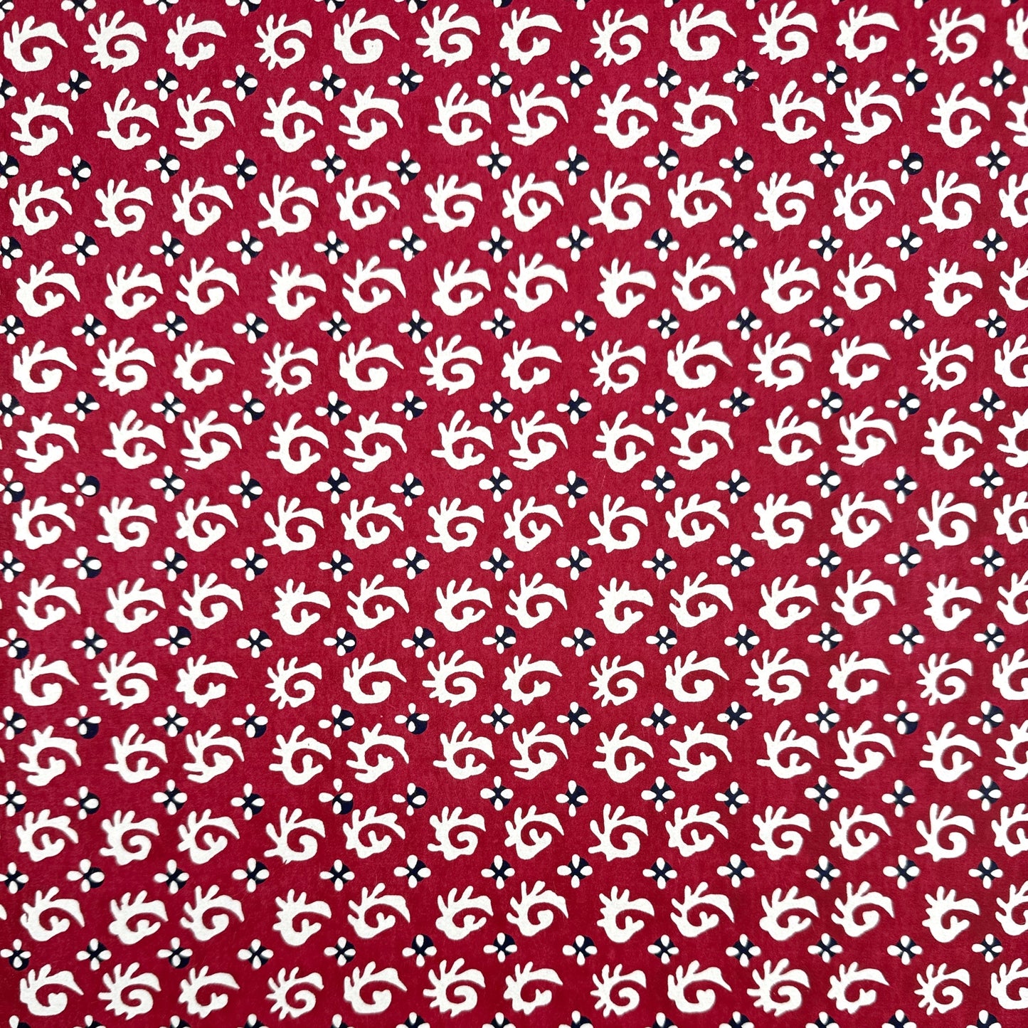 A Japanese stencil-dyed patterned paper with a repeat pattern in white on a deep rich red background.