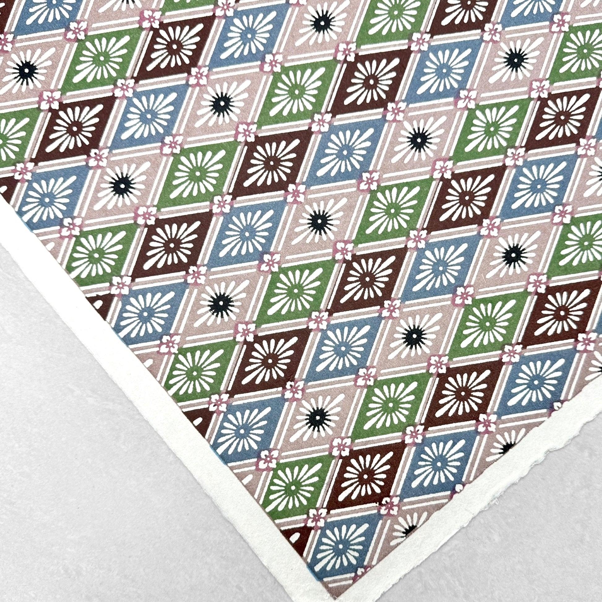 A Japanese stencil-dyed patterned paper with a repeat diamond floral pattern in blue, taupe, green and brown. Flat view