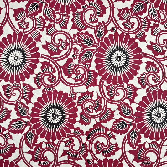 Japanese stencil-dyed paper with a repeat pattern of chrysanthemum flowers and swirling vines in deep berry red
