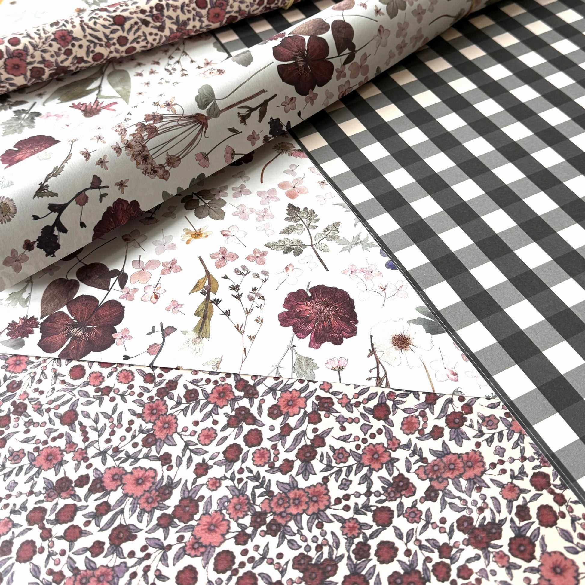 a sheet of wrapping paper with a black and white gingham pattern. Pictured with a floral pattern