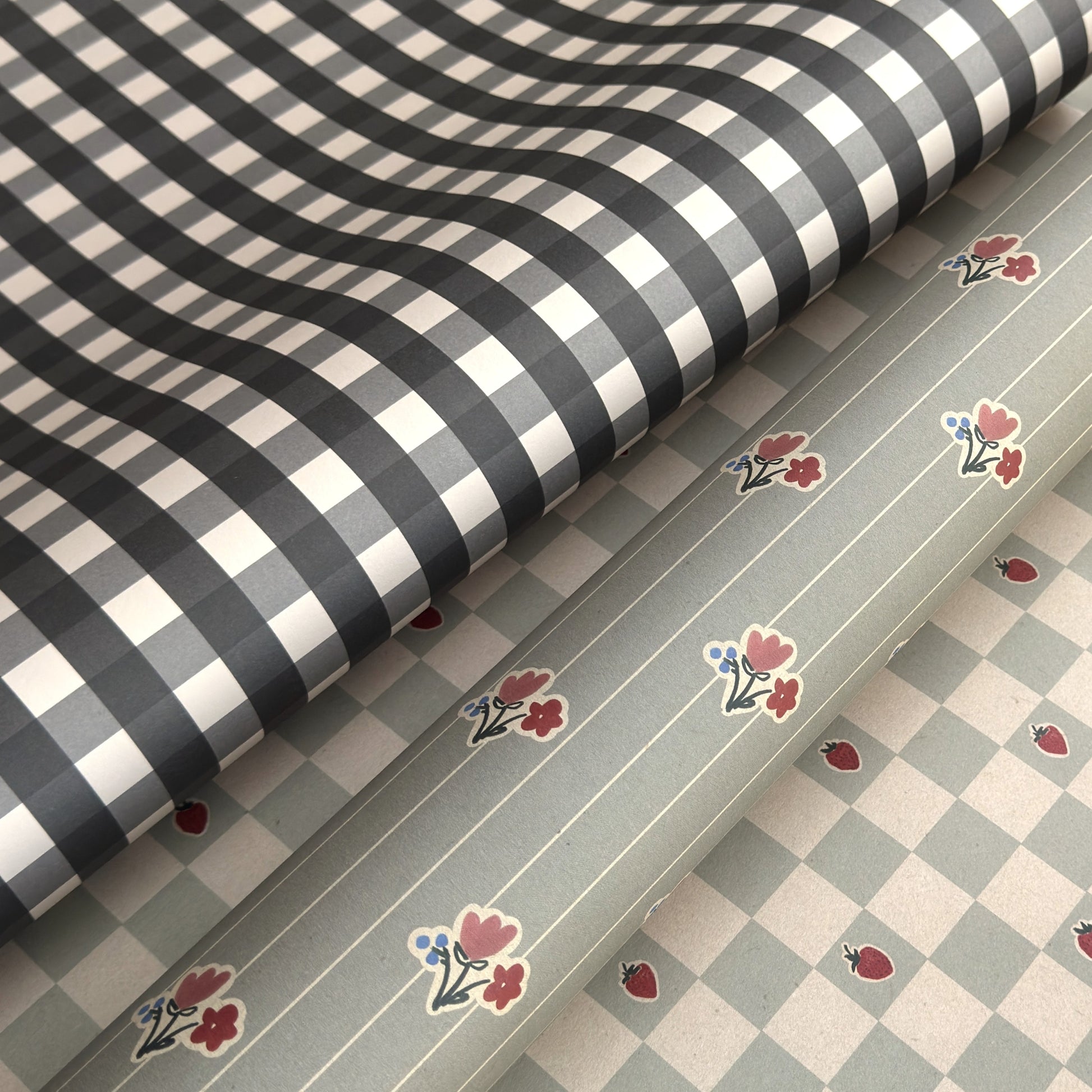 a sheet of wrapping paper with a black and white gingham pattern. Pictured with a floral pattern