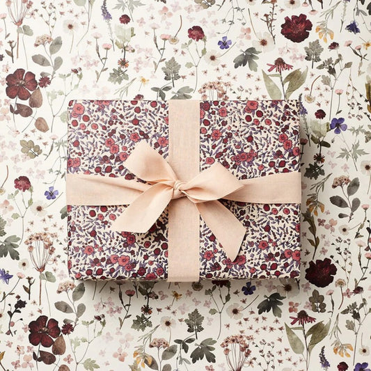 a sheet of wrapping paper with a pretty floral small scale rose design in pink and purple. wrapped with a bow