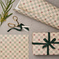 a sheet of wrapping paper with a soft green and cream checkered pattern with vintage style strawberries. Pictured wrapped