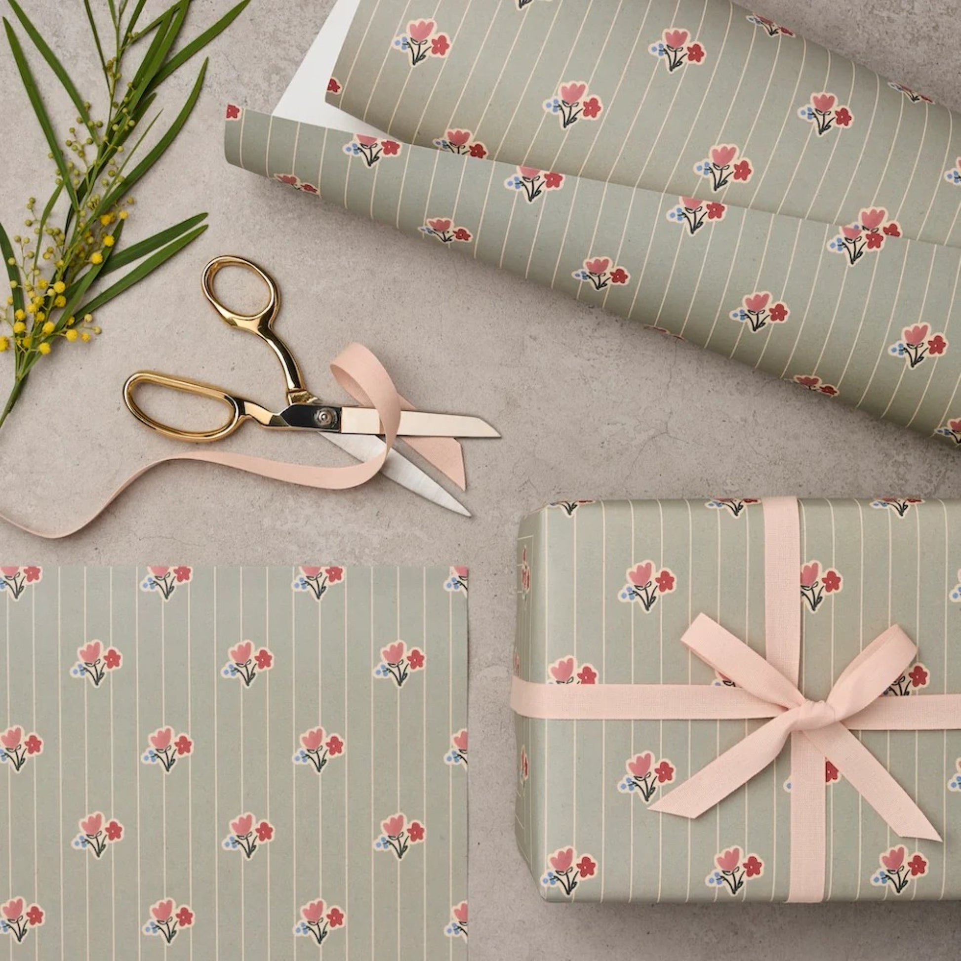 a sheet of wrapping paper with a soft grey-green stripe and pink and red vintage floral flowers. Pictured wrapped
