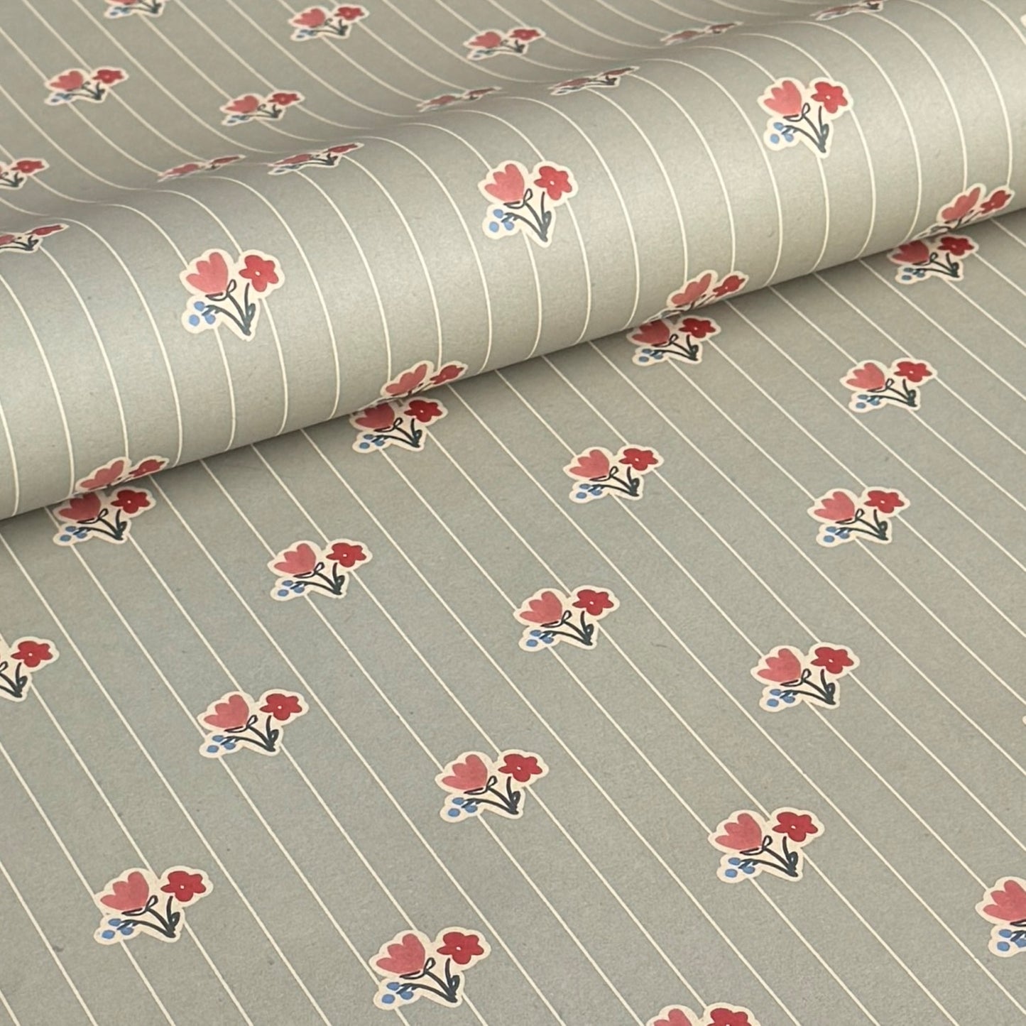 a sheet of wrapping paper with a soft grey-green stripe and pink and red vintage floral flowers