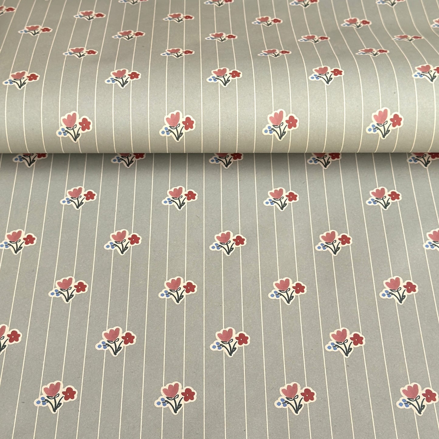 a sheet of wrapping paper with a soft grey-green stripe and pink and red vintage floral flowers