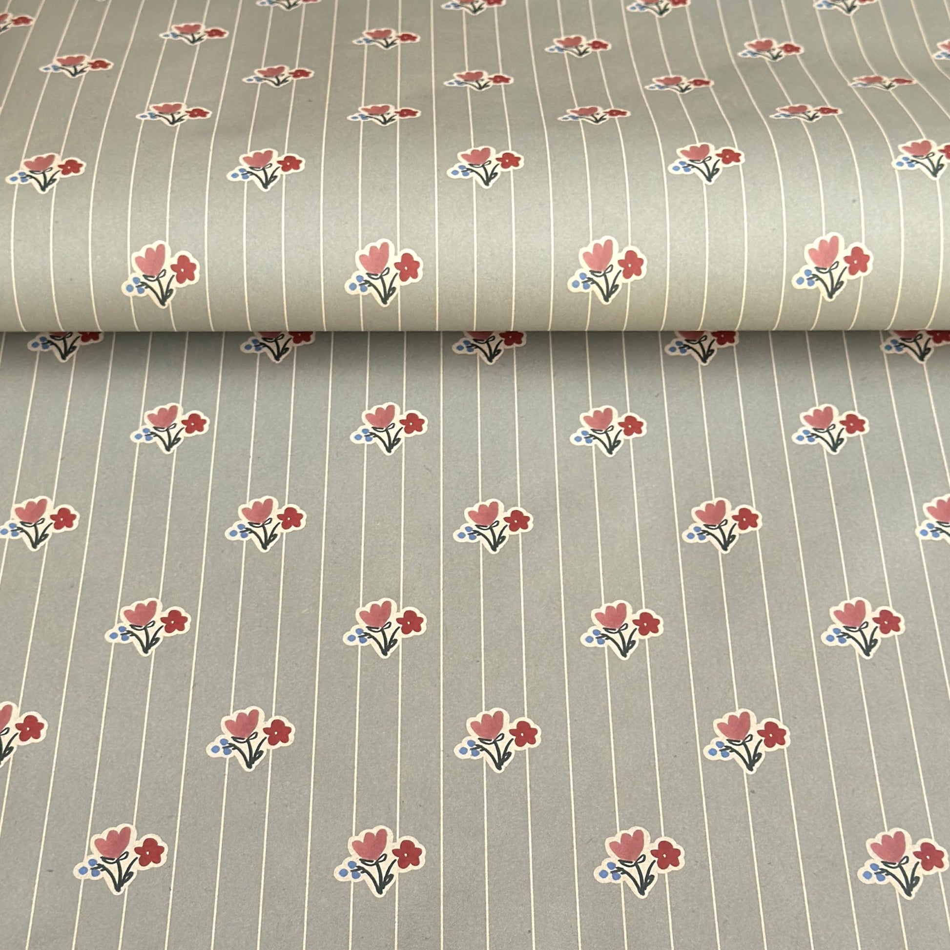a sheet of wrapping paper with a soft grey-green stripe and pink and red vintage floral flowers