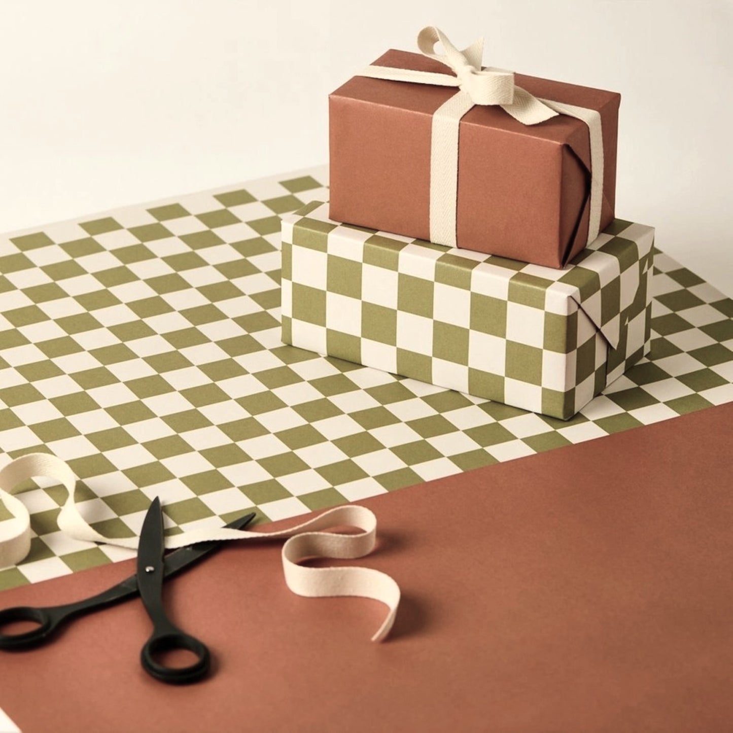 a sheet of wrapping paper with a green checkered pattern on the top half and plain cinnamon brown on the bottom