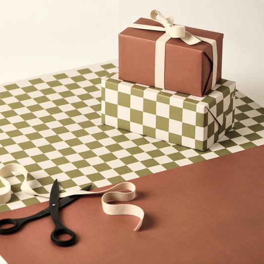 a sheet of wrapping paper with a green checkered pattern on the top half and plain cinnamon brown on the bottom