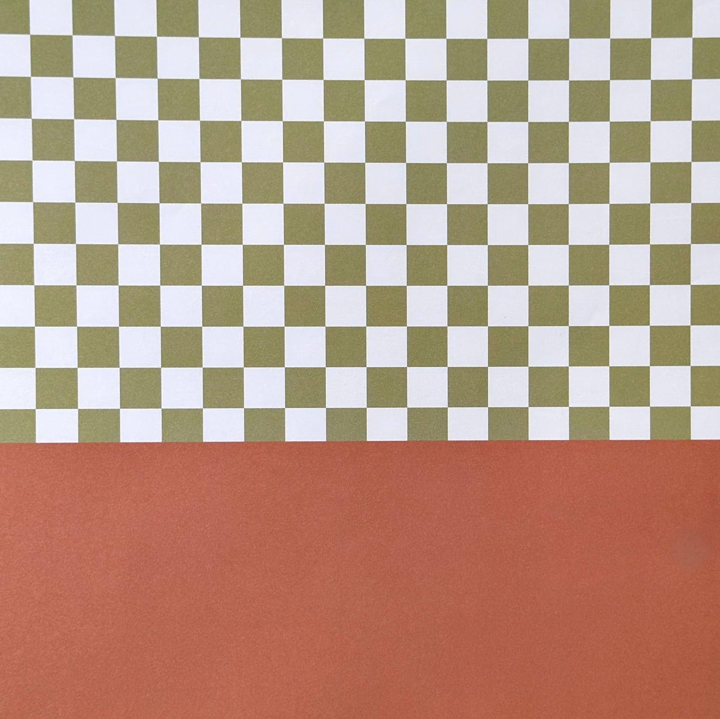 a sheet of wrapping paper with a green checkered pattern on the top half and plain cinnamon brown on the bottom