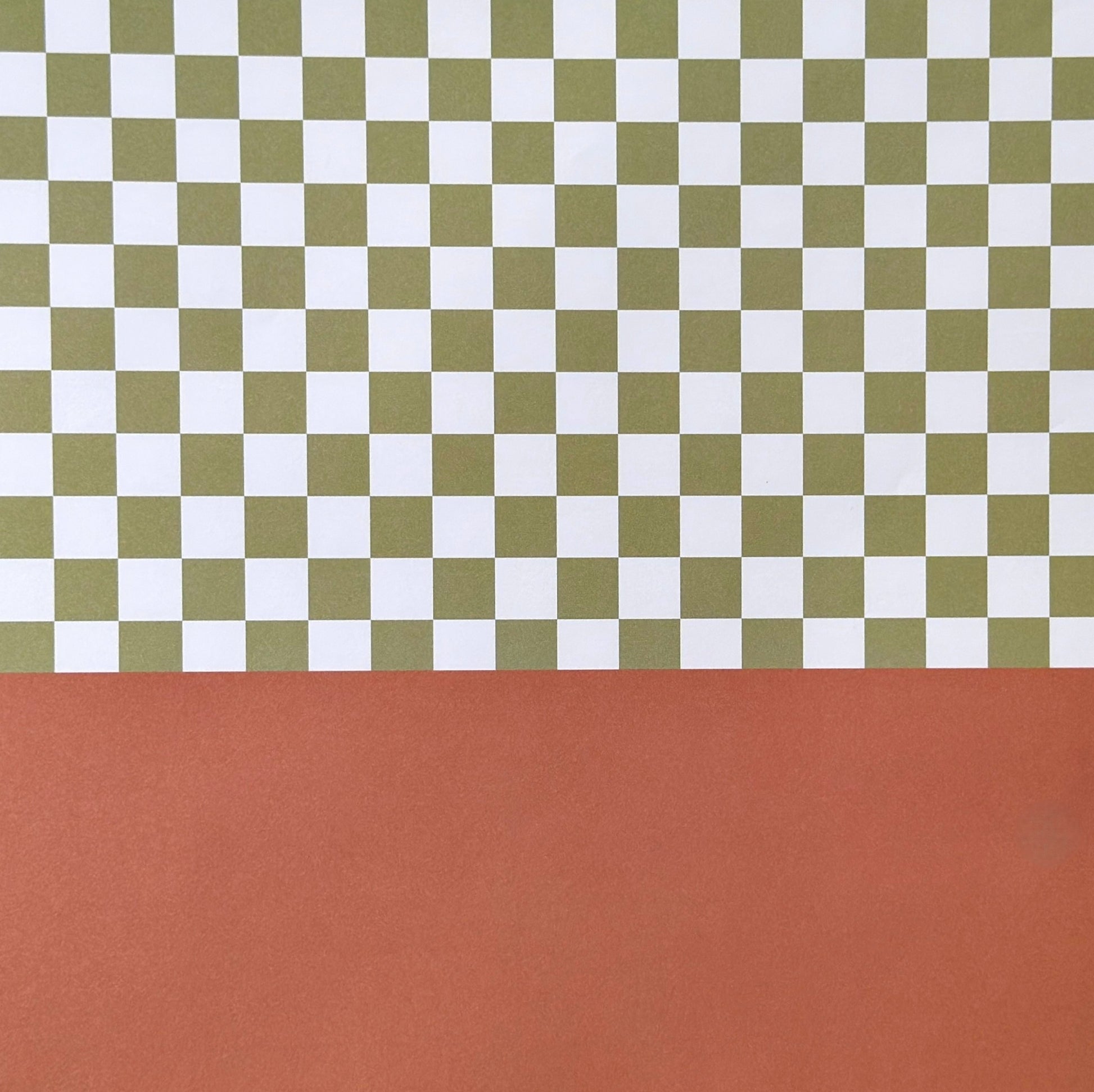 a sheet of wrapping paper with a green checkered pattern on the top half and plain cinnamon brown on the bottom