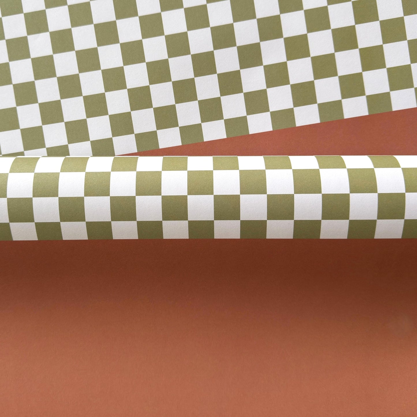 a sheet of wrapping paper with a green checkered pattern on the top half and plain cinnamon brown on the bottom