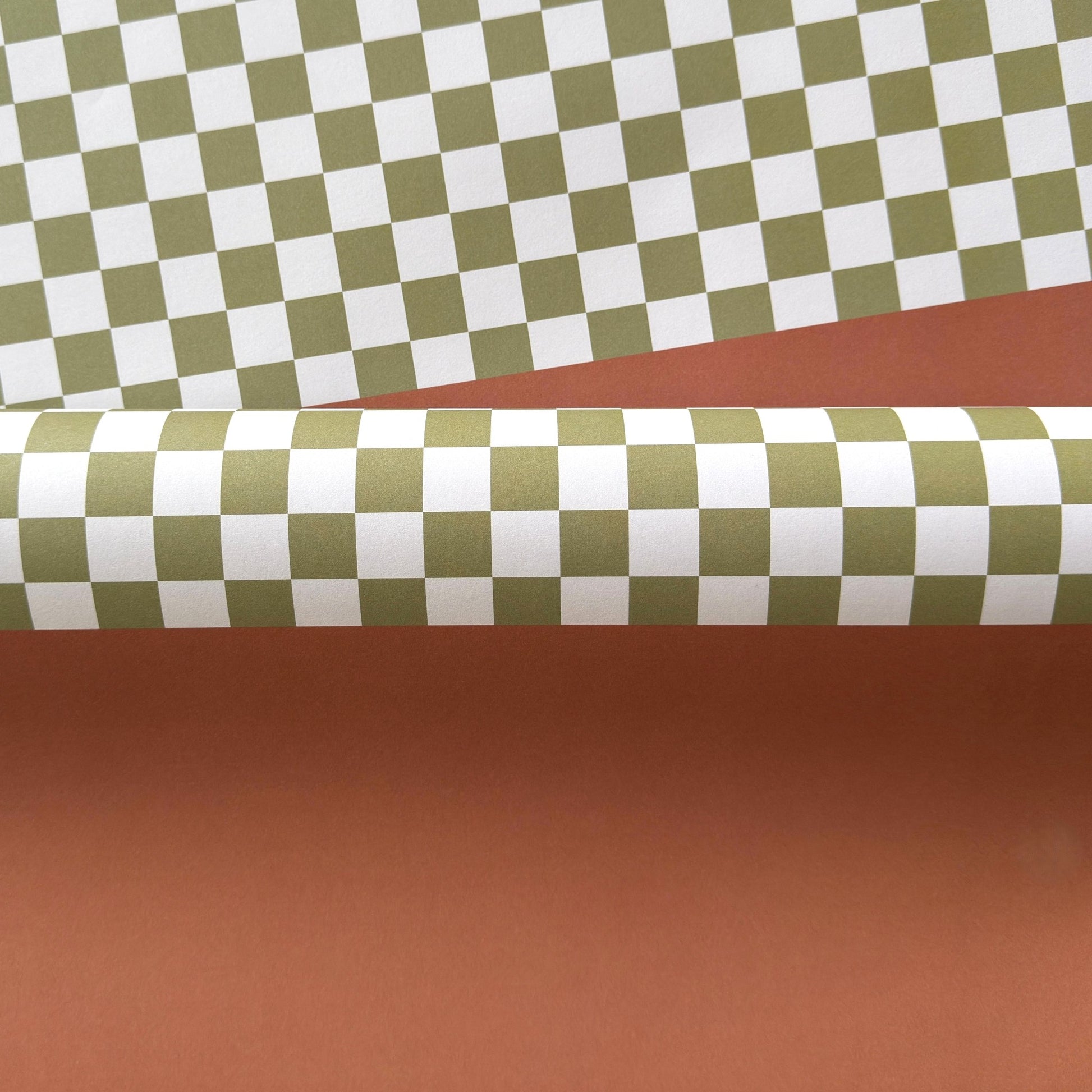 a sheet of wrapping paper with a green checkered pattern on the top half and plain cinnamon brown on the bottom