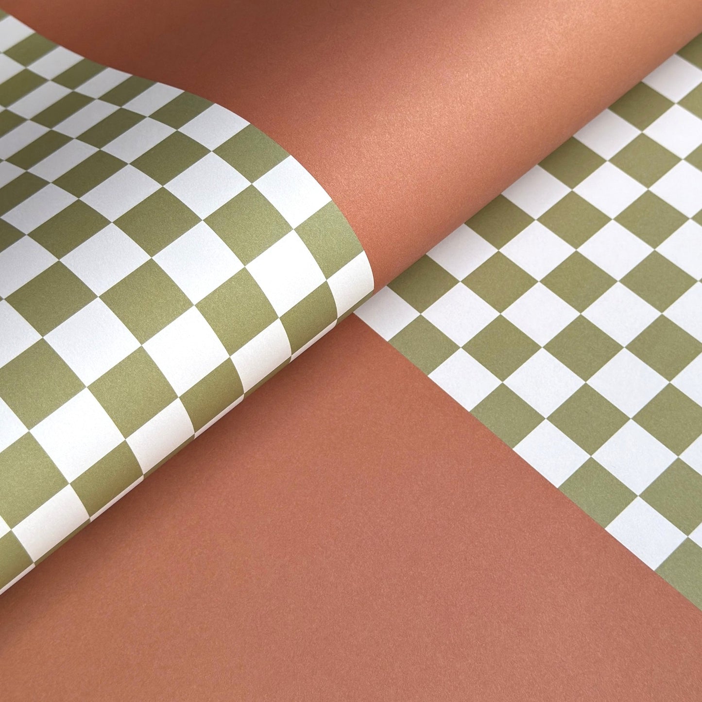 a sheet of wrapping paper with a green checkered pattern on the top half and plain cinnamon brown on the bottom