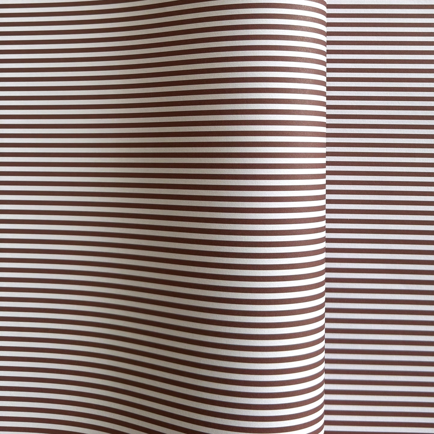 a sheet of wrapping paper with a narrow stripe design in dark brown and cream