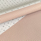 a sheet of wrapping paper with a split design, the top half has little black tile design on white and the bottom half a narrow stripe in cinnamon and white.