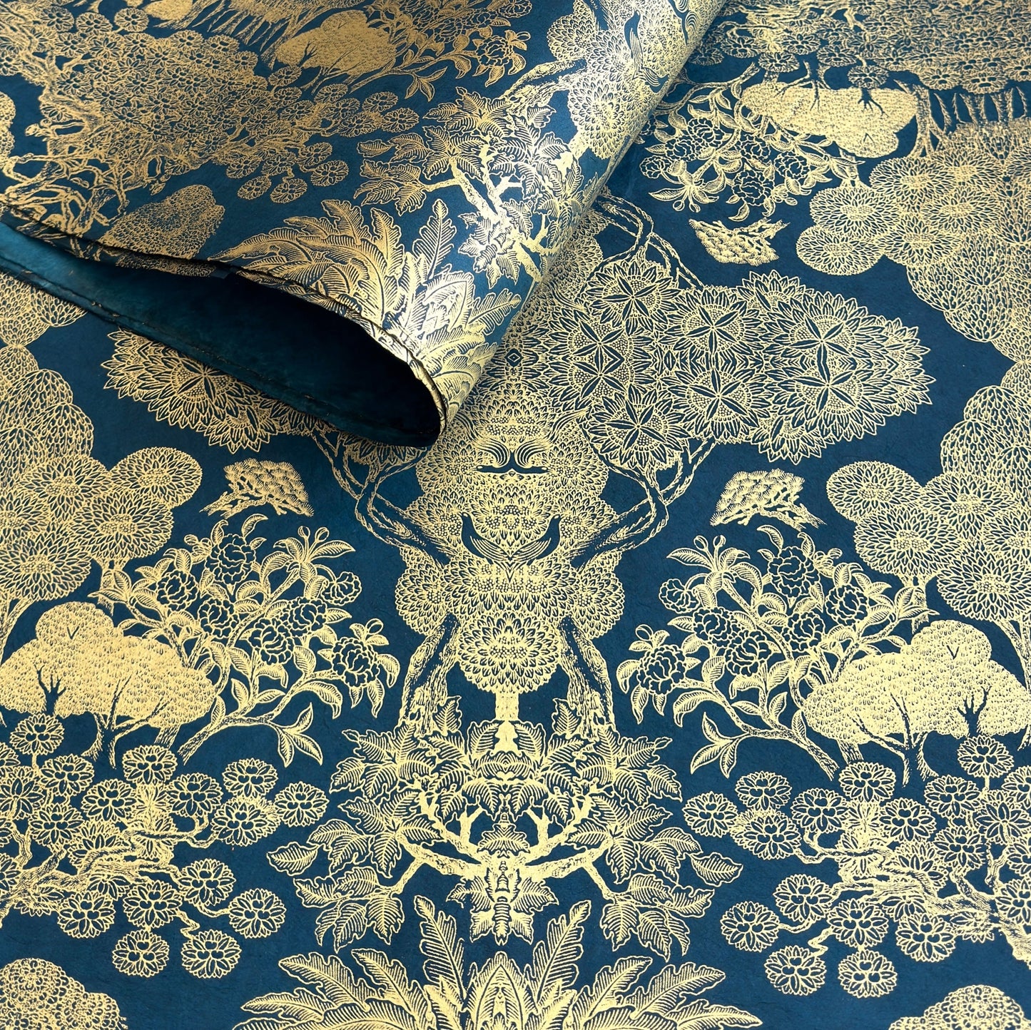 Nepalese handmade decorative lokta paper sheet with a detailed design of trees and flowers in gold metallic screen printed on a midnight blue lokta paper.