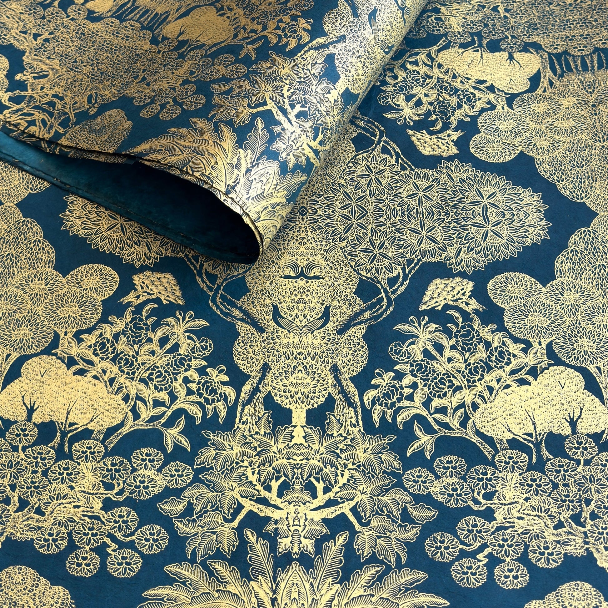 Nepalese handmade decorative lokta paper sheet with a detailed design of trees and flowers in gold metallic screen printed on a midnight blue lokta paper.