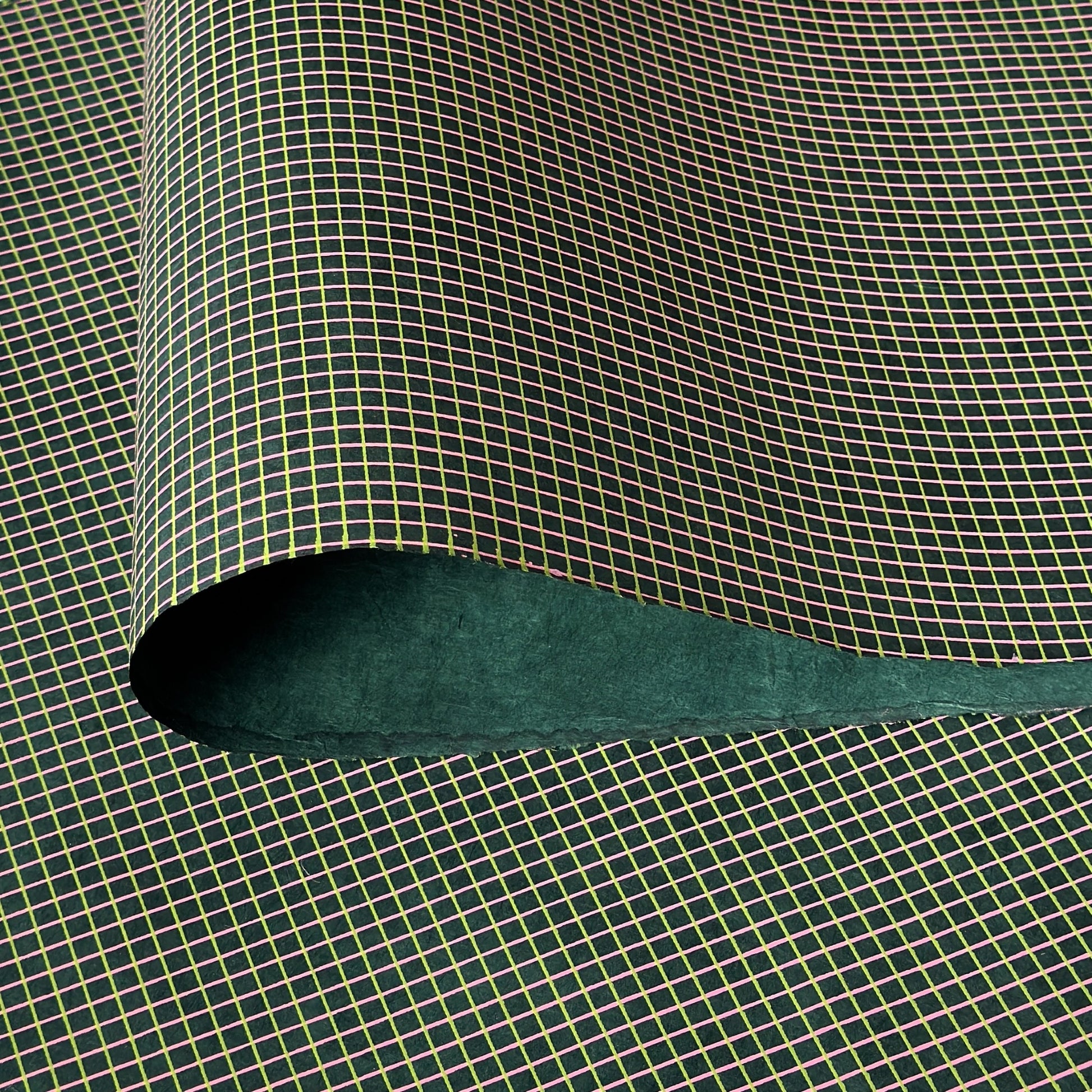 a sheet of Nepalese lokta paper with a lime green and pink grid pattern on dark green handmade paper
