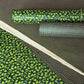 a sheet of Nepalese lokta paper with a lime green and pink grid pattern on dark green handmade paper. Pictured alongside a floral paper