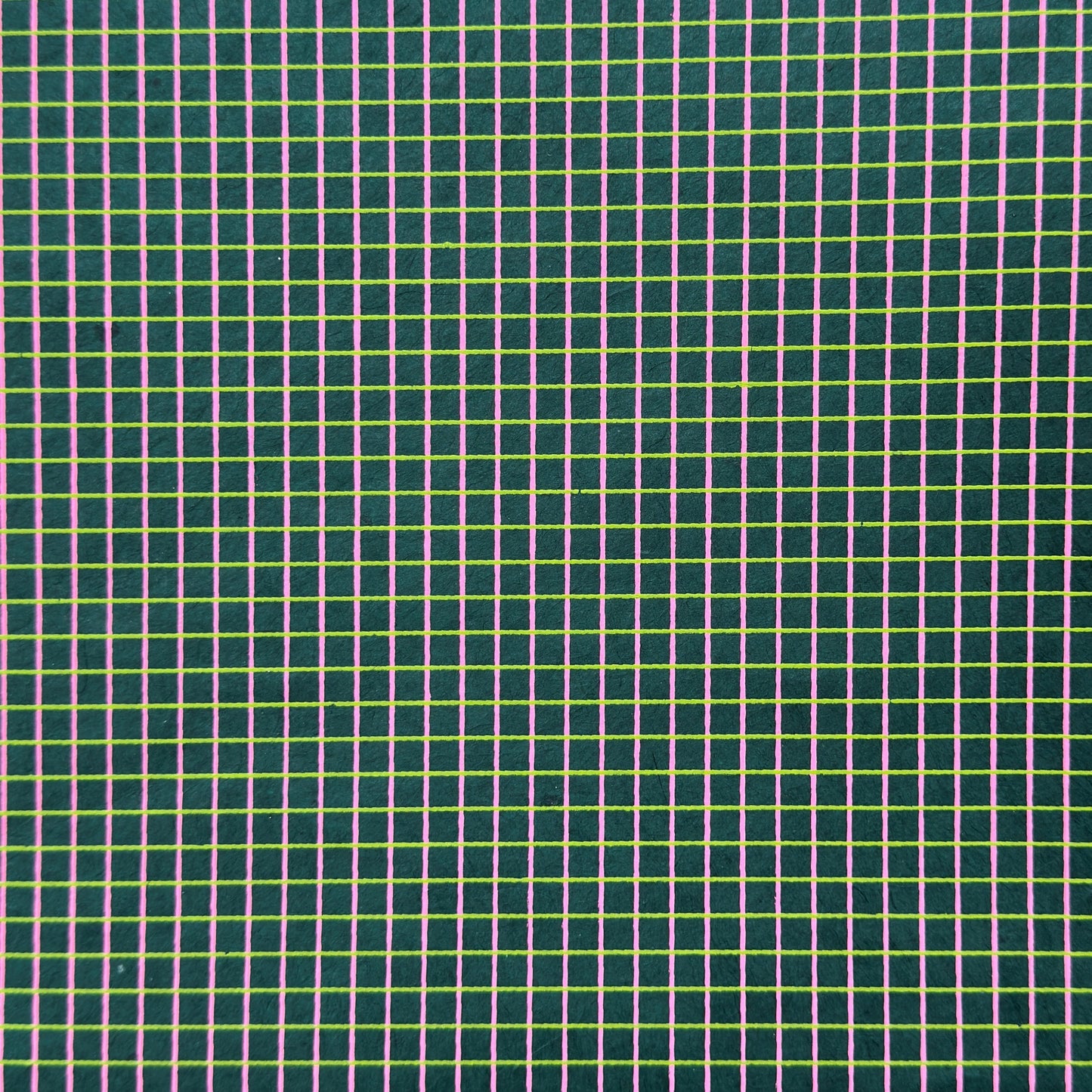 a sheet of Nepalese lokta paper with a lime green and pink grid pattern on dark green handmade paper. Close up