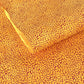 a sheet of screen printed Nepalese lokta paper with a repeat floral design in dark orange on an amber yellow lokta paper 