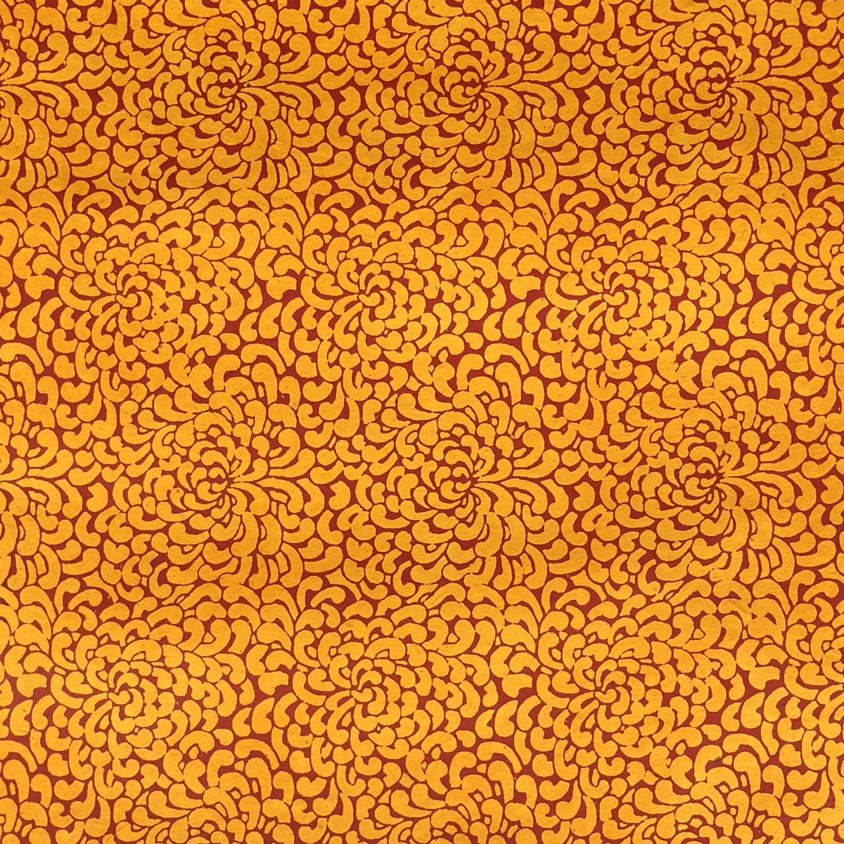a sheet of screen printed Nepalese lokta paper with a repeat floral design in dark orange on an amber yellow lokta paper 