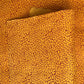 a sheet of screen printed Nepalese lokta paper with a repeat floral design in dark orange on an amber yellow lokta paper 