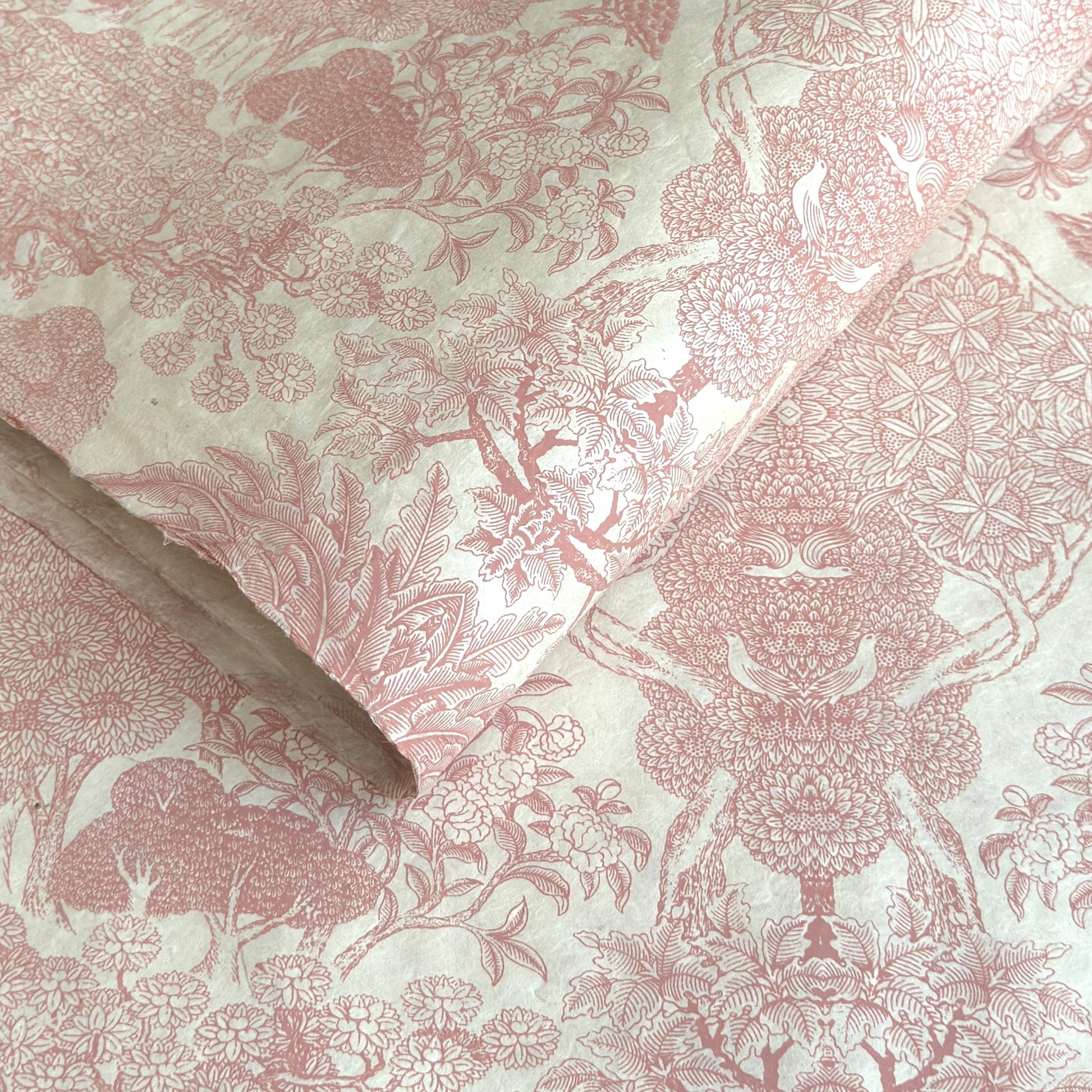 Nepalese handmade decorative lokta paper sheet with a detailed design of trees and flowers in blush pink screen printed on an ivory lokta paper.