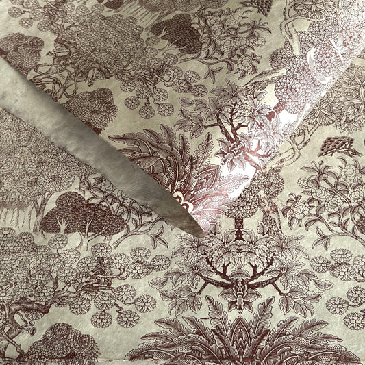 A sheet of Nepalese handprinted Lokta paper with a detailed pattern of trees and flowers in sepia on an ecru base.