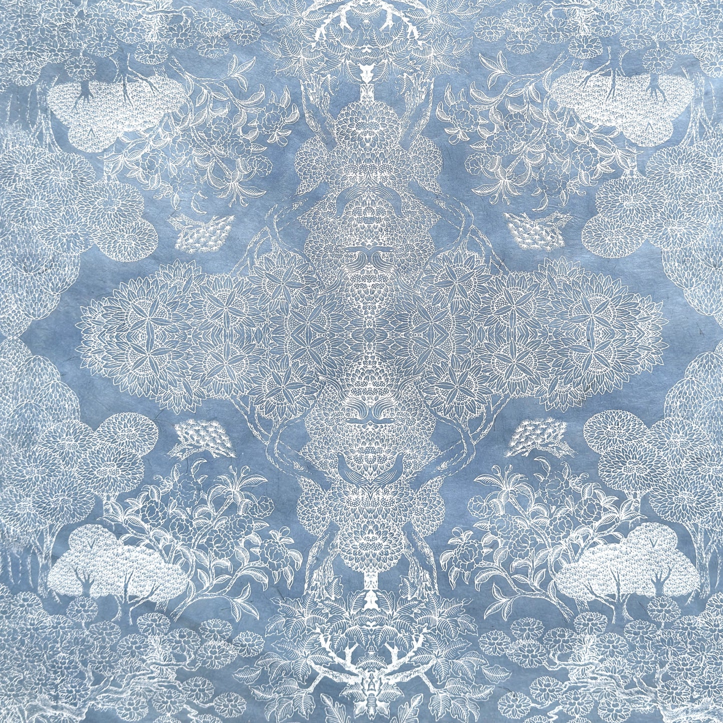 a sheet of Nepalese lokta paper in sky blue with a detailed pattern of trees and flowers screen printed in white